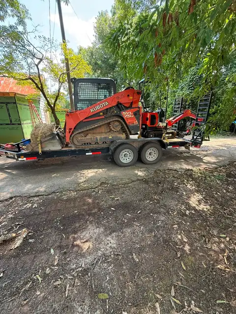 Compact track loader on a trailer at a job site
