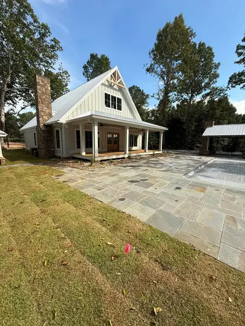 Sod and a flagstone patio behind a farmhouse