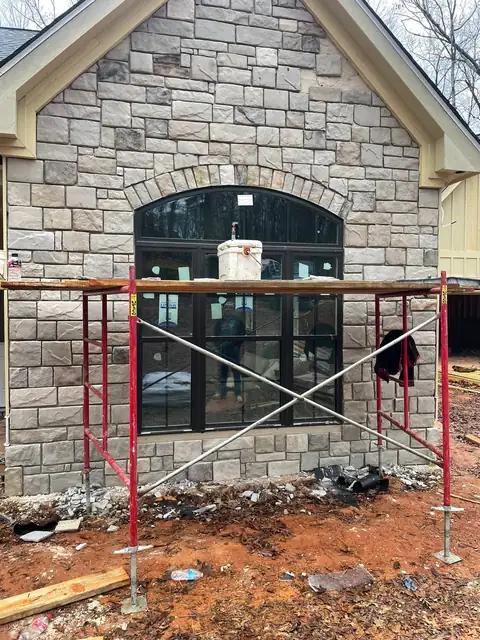 Stone veneer going up around an arched window