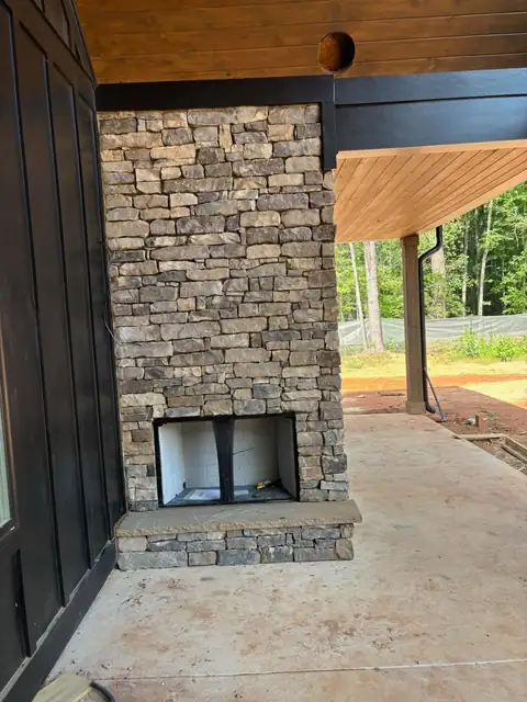 Stacked stone fireplace on a covered porch