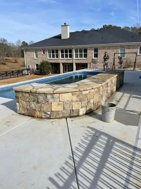 Curved stacked stone wall along the edge of the pool