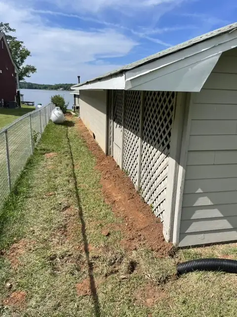 Drain line trenched along the side of the house toward the lake
