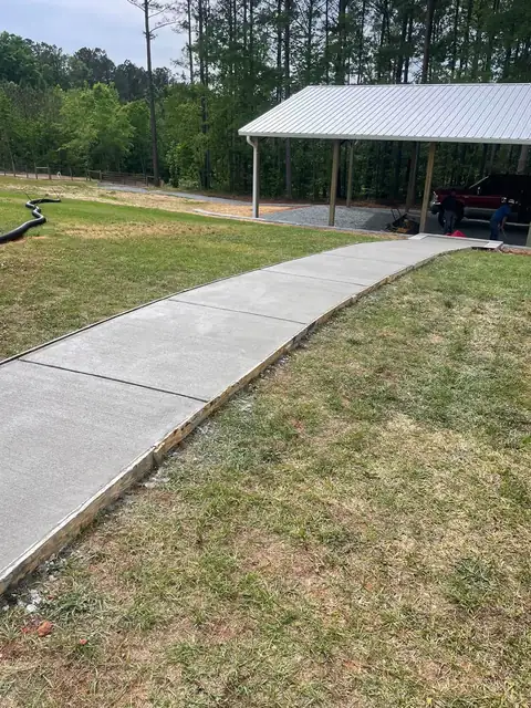 Concrete walkway curving across a lawn to a carport