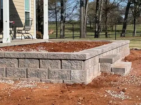 Block retaining wall with built-in steps around a raised patio